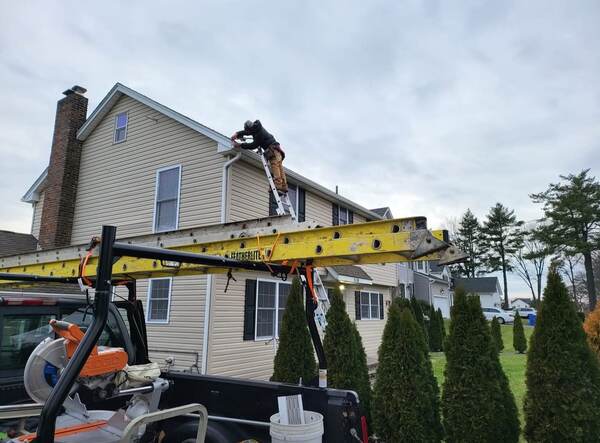 Gutter installer working at the eave with boom-assisted material lift